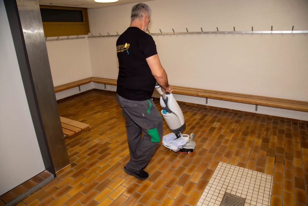 Mann reinigt gefliesten Boden mit Bodenmaschine.
